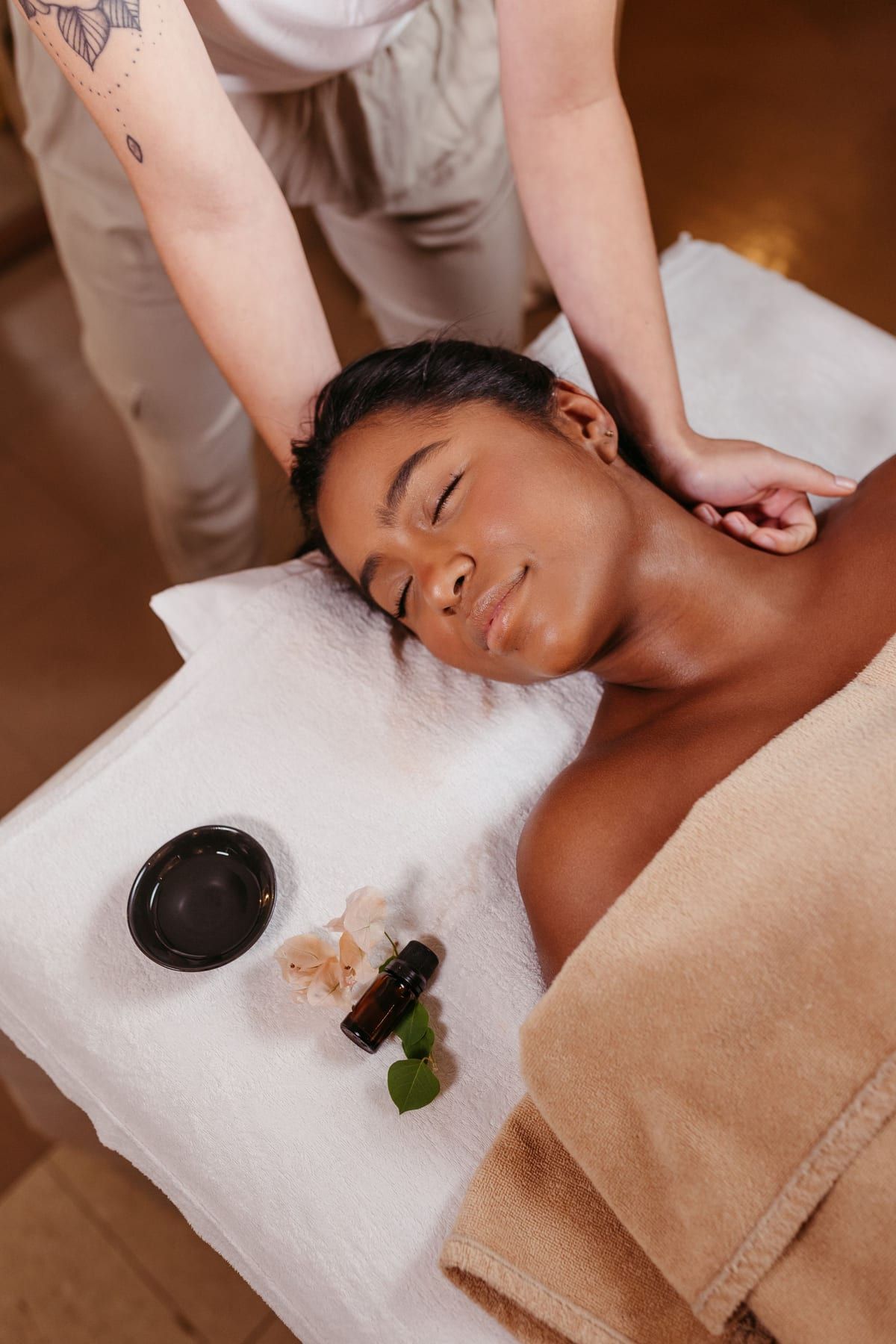 Personne détendue, yeux fermés, pendant un massage des épaules, avec huile essentielle et serviette blanche à côté